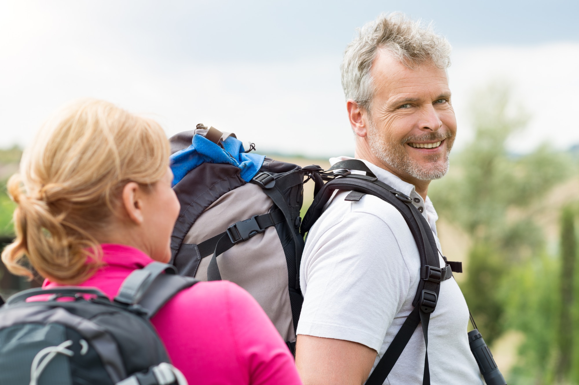 Happy Mature Man Wearing Backpack Hiking With Wife